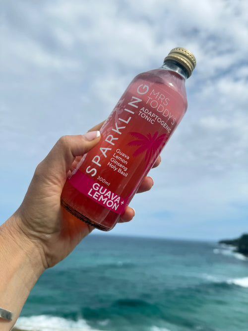 Plant-based sparkling drink in glass bottle with guava, lemon, and ginger