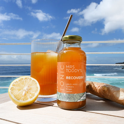 Glass bottle of turmeric, lemon and ginger tonic with cinnamon and black pepper